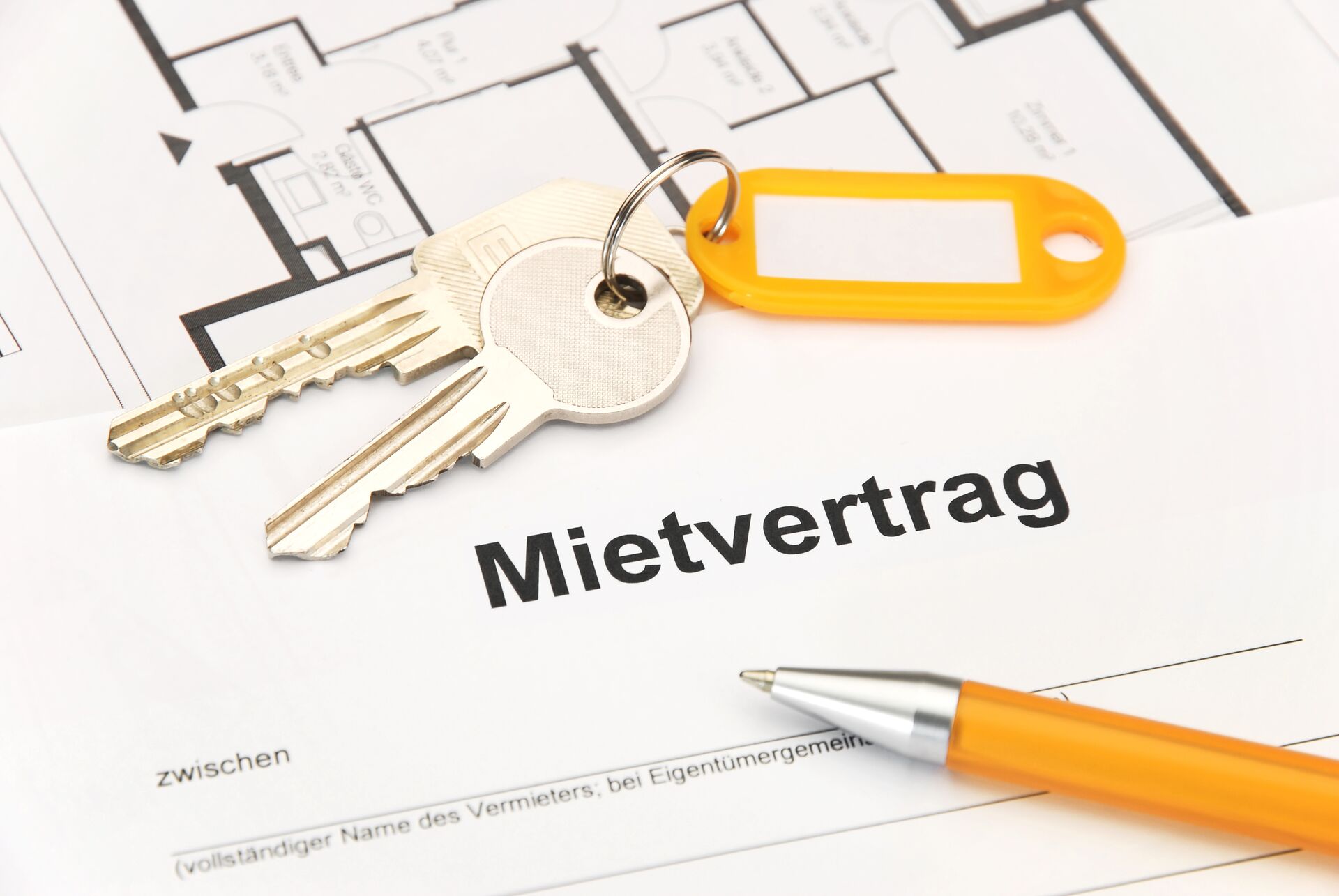 Ein Schlüssel und ein orangener Kugelschreiber liegen auf einem Mietvertrag